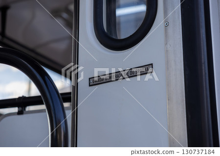A bright public transport interior door displaying an essential warning sign, UWAGA OTWIERAJA SIE DO SRODKA, providing crucial directional information for daily safe passenger journey 130737184