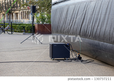 Outdoor public event setup displays portable sound and visual equipment, including a speaker on a tripod and a subwoofer for live entertainment Outdoor public event setup displays portable sound and visual equipment, including a speaker on a tripod and a subwoofer for live entertainment 130737211