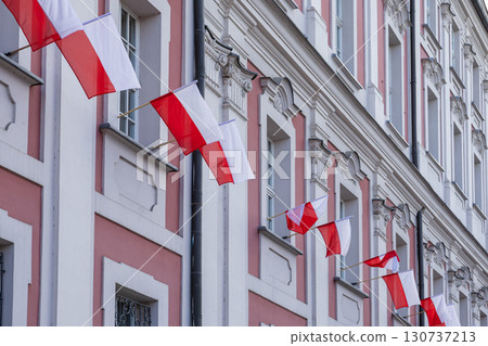 Multiple vibrant Polish flags proudly displayed on an elegant historic building facade, symbolizing national pride, patriotism, and European heritage Multiple vibrant Polish flags proudly displayed on an elegant historic building facade, symbolizing national pride, patriotism, and European heritage 130737213