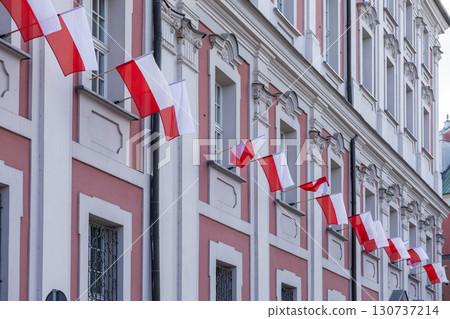 Ornate historic building facade prominently displaying many vibrant red and white Polish flags, symbolizing national independence, patriotism, and European cultural heritage 130737214