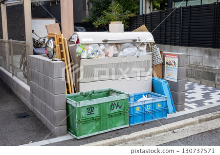 A garbage dumpster in an apartment complex filled with garbage A garbage dumpster in an apartment complex filled with garbage 130737571