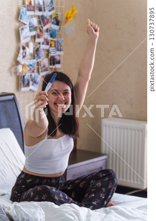 Surprised Woman with Positive Pregnancy Test 130737895
