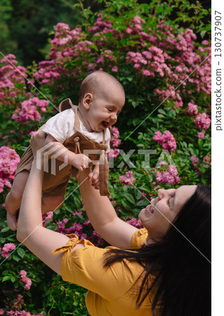 Joyful Mother and Baby in Blooming Garden Joyful Mother and Baby in Blooming Garden 130737907