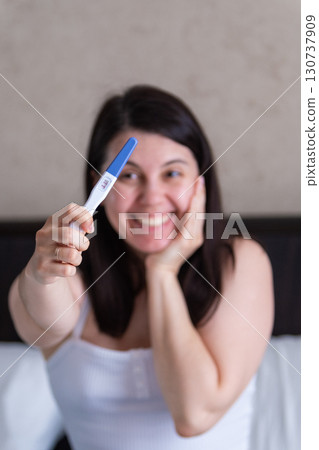 Surprised Woman with Positive Pregnancy Test Surprised Woman with Positive Pregnancy Test 130737909