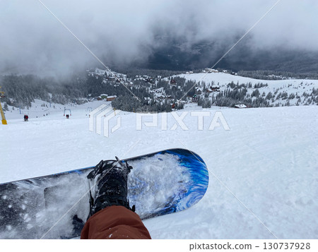 Snowboarder on Slope Overlooking Ski Resort Snowboarder on Slope Overlooking Ski Resort 130737928