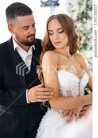 Beautiful and gentle bride and groom on the background of flowers in the decor. Beautiful and gentle bride and groom on the background of flowers in the decor. 130738057