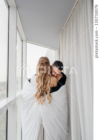 A gentle and romantic man and woman wrapped in a blanket on the windowsill 130738076