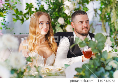 The bride and groom at the newlyweds' table, decorated with many flowers.  130738078