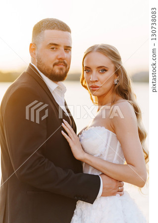 Gentle and happy bride and groom at sunset on the riverbank. Romantic. 130738083