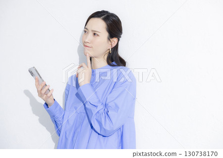 一位年輕女子正在看智慧型手機，遇到了麻煩 130738170