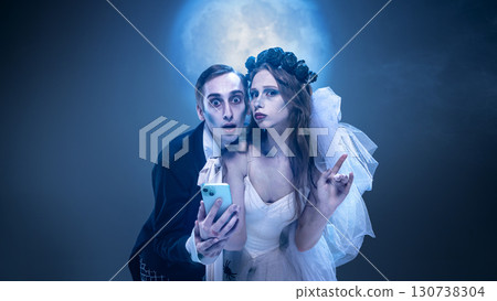 Surreal gothic couple with smartphone under moonlight in theatrical costume spooky portrait 130738304
