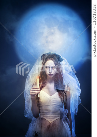 Gothic bride with black crown posing with candle in moonlight 130738318