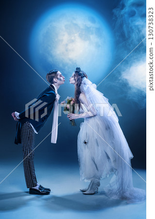 Gothic couple facing each other with bouquet in misty moonlight scene Gothic couple facing each other with bouquet in misty moonlight scene 130738323