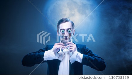 Surreal groom holding eyeballs with theatrical expression under full moon 130738329