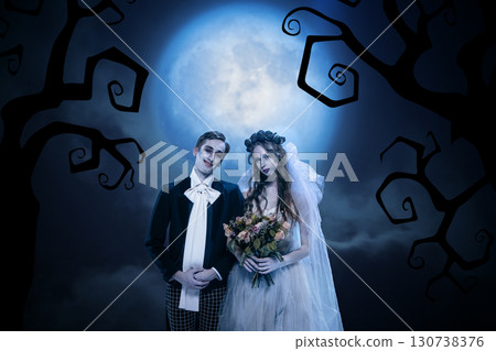Gothic bride and groom holding bouquet in surreal moonlit wedding scene 130738376