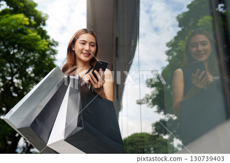 Shopping and Digital Engagement. Young woman enjoying shopping experience with smartphone. Shopping and Digital Engagement. Young woman enjoying shopping experience with smartphone. 130739403