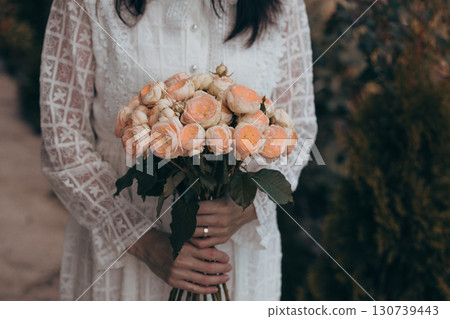 Bouquet in female hands. Bunch of Living Coral roses. 130739443