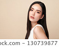 A beautiful young Asian woman with clean, fresh skin against a beige background. Skincare, facial treatment, cosmetology, beauty, and spa. An elegant portrait of an Asian woman. 130739877
