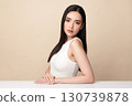 A beautiful young Asian woman with clean, fresh skin against a beige background. Skincare, facial treatment, cosmetology, beauty, and spa. An elegant portrait of an Asian woman. 130739878