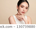 A beautiful young Asian woman with clean, fresh skin against a beige background. Skincare, facial treatment, cosmetology, beauty, and spa. An elegant portrait of an Asian woman. 130739880