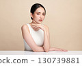 A beautiful young Asian woman with clean, fresh skin against a beige background. Skincare, facial treatment, cosmetology, beauty, and spa. An elegant portrait of an Asian woman. 130739881