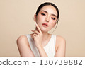 A beautiful young Asian woman with clean, fresh skin against a beige background. Skincare, facial treatment, cosmetology, beauty, and spa. An elegant portrait of an Asian woman. 130739882