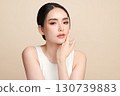A beautiful young Asian woman with clean, fresh skin against a beige background. Skincare, facial treatment, cosmetology, beauty, and spa. An elegant portrait of an Asian woman. 130739883