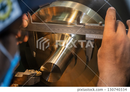 Close up scene the machine operator measuring dimension of metal shaft parts by Vernier caliper. 130740334