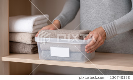 Hands organizing folded towels neatly in storage box Hands organizing folded towels neatly in storage box 130740358