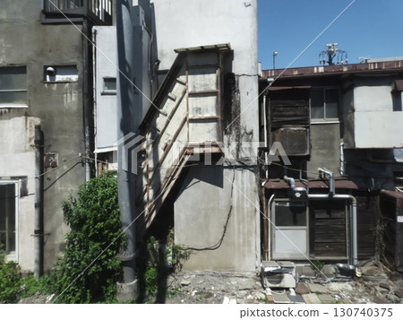 A rusty staircase nestled quietly among dilapidated buildings 130740375