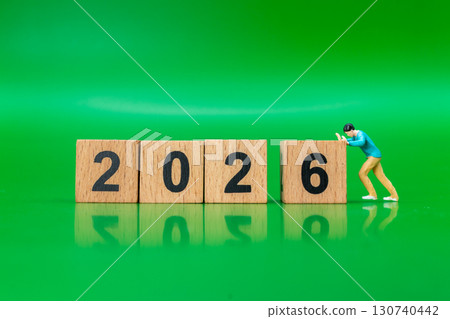 Miniature Figure Pushing Wooden Blocks to Form 2026 on Green Background Miniature Figure Pushing Wooden Blocks to Form 2026 on Green Background 130740442