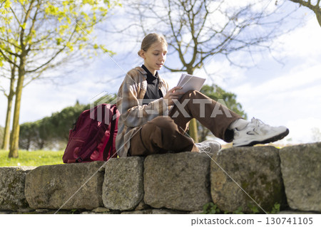 Young student reading notes outdoors in a park Young student reading notes outdoors in a park 130741105