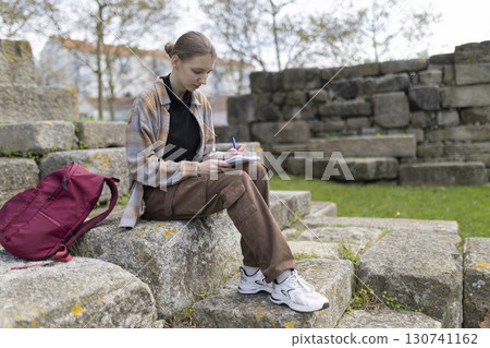 Archaeologist writing notes while sitting on ancient ruins Archaeologist writing notes while sitting on ancient ruins 130741162