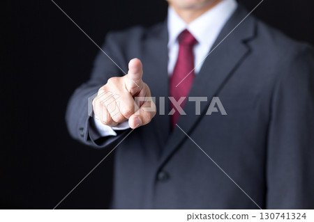 Middle-aged male businessman in a suit pointing Middle-aged male businessman in a suit pointing 130741324