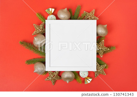White frame with Christmas tree ornaments and green Christmas tree branches on a red background for text, greetings, offers, discounts, and advertisements. White frame with Christmas tree ornaments and green Christmas tree branches on a red background for text, greetings, offers, discounts, and advertisements. 130741343