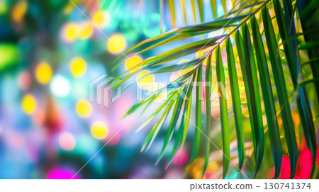 Vibrant green palm leaf against colorful bokeh background, evoking tropical party vibe. Playful contrast suggests festive concept, suitable for summer event invitations or exotic-themed promotions 130741374
