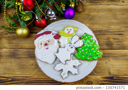 Christmas gingerbread cookies in a plate and Christmas decoration on a wooden table. Top view Christmas gingerbread cookies in a plate and Christmas decoration on a wooden table. Top view 130741571