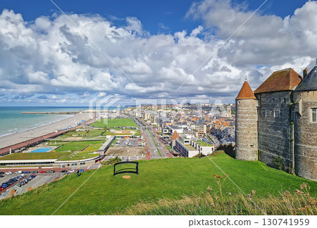 An elevated view captures Dieppe and its coastline. The historic stone castle with pointed towers overlooks the town and urban streets leading to a long pebble beach and the English Channel 130741959