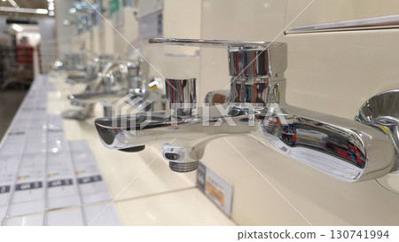 Chrome bathroom faucet display in store aisle with modern fixtures and design options Chrome bathroom faucet display in store aisle with modern fixtures and design options 130741994