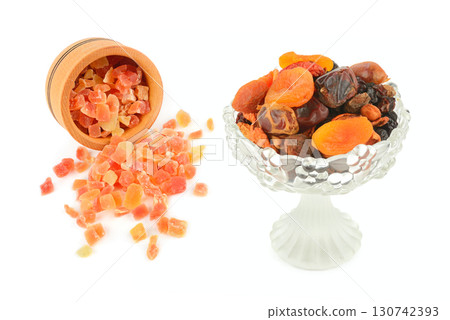 Dried and candied fruits in a glass vase and on a wooden plate. Dried and candied fruits in a glass vase and on a wooden plate. 130742393
