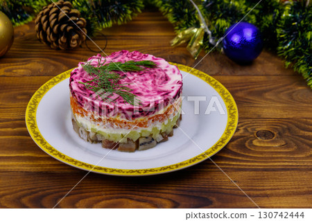 Traditional russian salad "Herring under a fur coat" (shuba) and Christmas decorations on wooden table 130742444