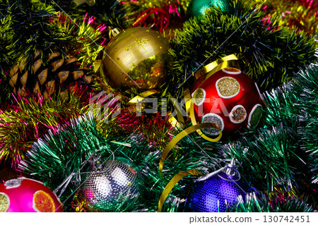 Christmas composition with Christmas baubles and multicolored tinsel. Christmas balls in bright tinsel close-up Christmas composition with Christmas baubles and multicolored tinsel. Christmas balls in bright tinsel close-up 130742451