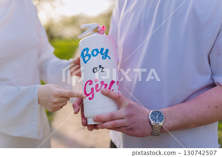 Couple revealing baby gender with color spray during gender reveal celebration outdoors 130742507