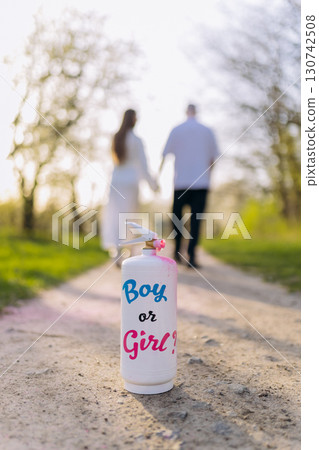 Gender reveal concept with a spray can and couple walking hand in hand in soft sunlight 130742508