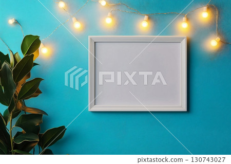 White frame is hanging on a turquoise wall with string lights and a green plant, perfect for showcasing your designs White frame is hanging on a turquoise wall with string lights and a green plant, perfect for showcasing your designs 130743027