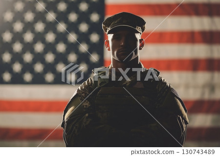 Proud American soldier is posing in front of the USA flag waving in the background 130743489
