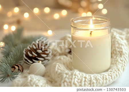 White candle burning in a glass jar surrounded by Christmas decorations, evoking a cozy and festive atmosphere White candle burning in a glass jar surrounded by Christmas decorations, evoking a cozy and festive atmosphere 130743503