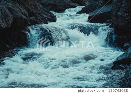 Rapid mountain river flowing over rocks, showcasing nature's power and beauty on a sunny day 130743688