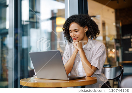 A Focused Professional Woman Working Diligently on Her Laptop in a Modern Cafe Setting A Focused Professional Woman Working Diligently on Her Laptop in a Modern Cafe Setting 130744108