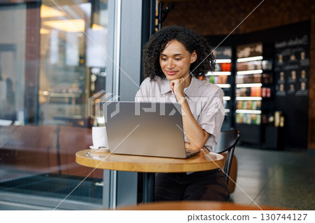 Concentrated Woman Diligently Working on Her Laptop While Enjoying a Cafe Atmosphere Concentrated Woman Diligently Working on Her Laptop While Enjoying a Cafe Atmosphere 130744127